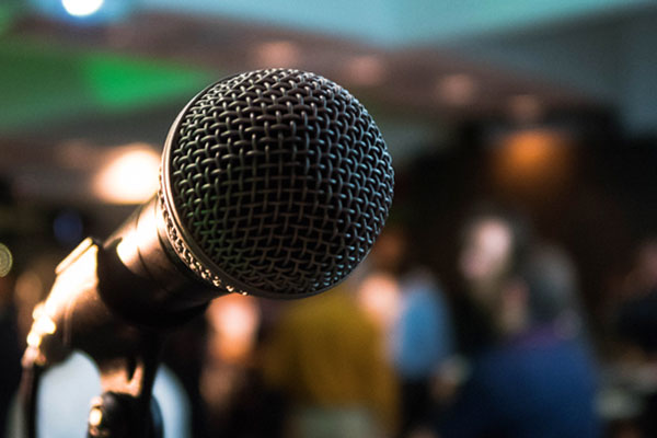 A photo of a microphone against a blurry background with a crowd visible