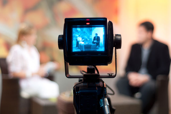 A photo of a video camera recording an interview with blurred background